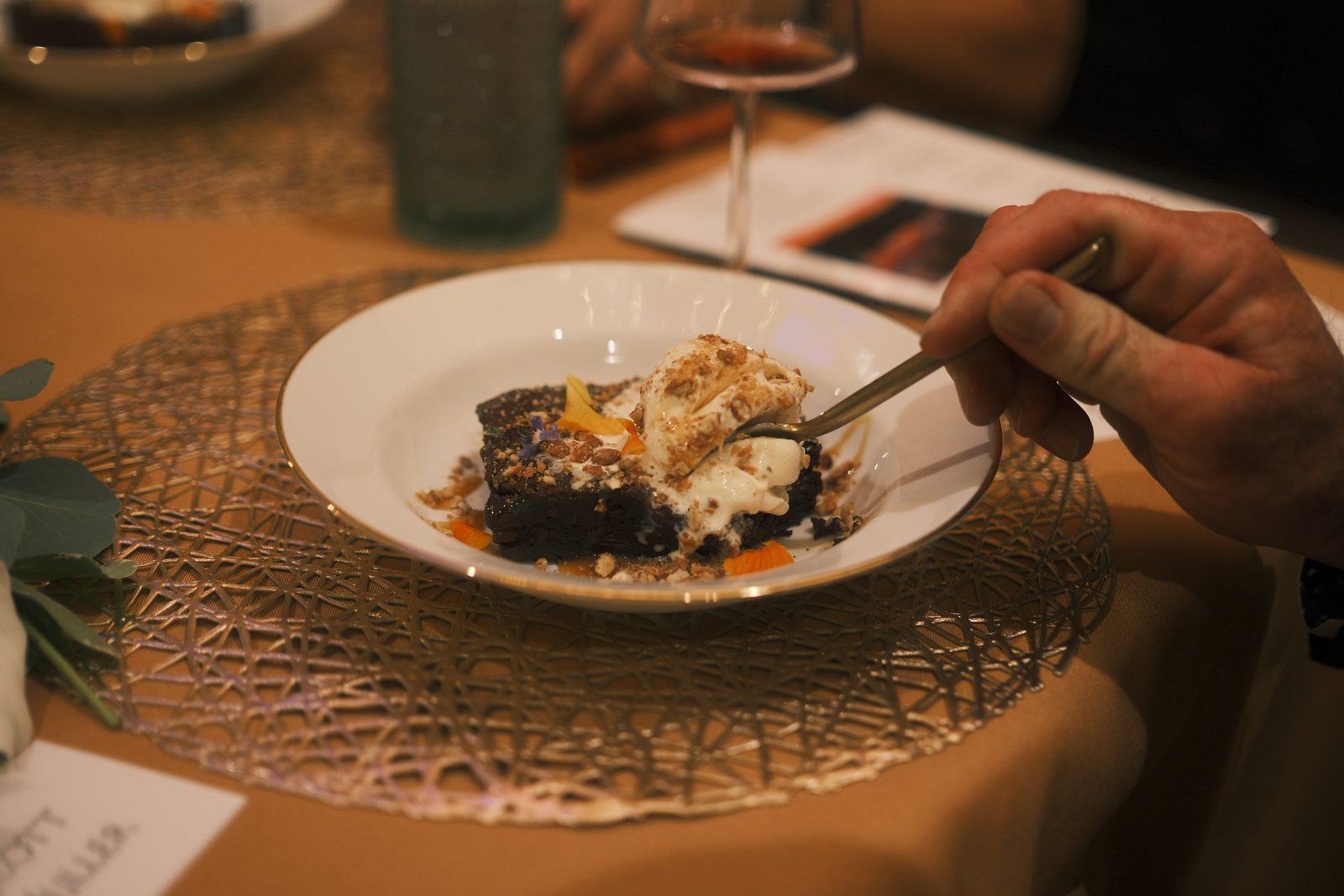 A guest at a candlelit dinner reaching into a plated dessert