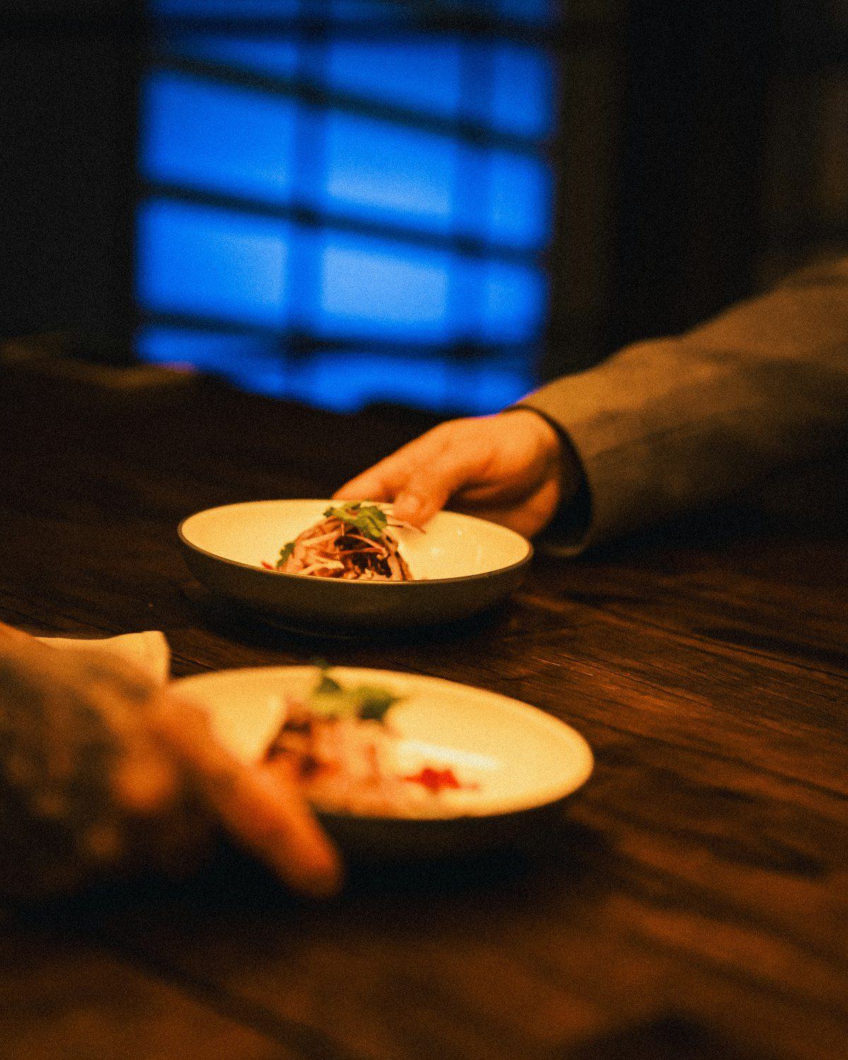Hands passing plates of food across a dinner table