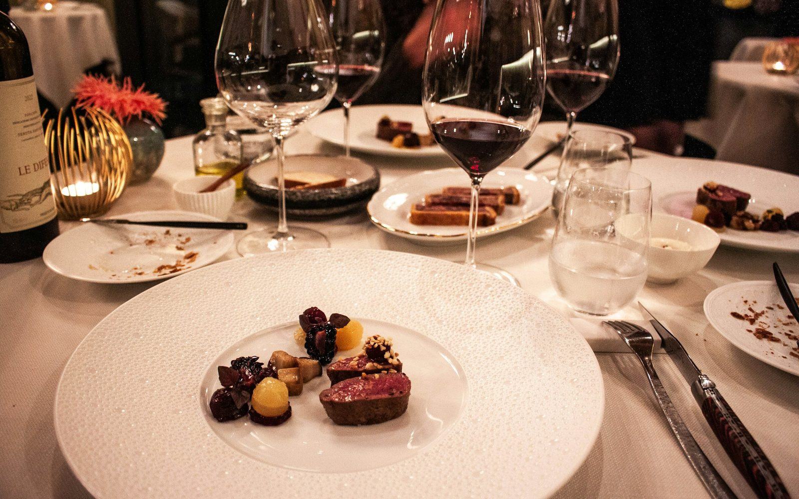 A plated dish and a glass of red wine at a set table